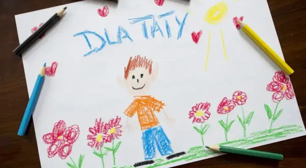 Dziecko narysowało dla taty chłopca w pomarańczowej koszulce i niebieskich spodniach, otoczonego kwiatami i serduszkami.
