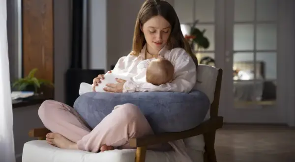 Młoda mama karmi piersią dziecko, skupiona na maluszku. Czy botoks a karmienie piersią to bezpieczne połączenie?