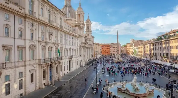 Una vivace piazza barocca a Roma, con la Fontana dei Quattro Fiumi al centro e la chiesa di Sant'Agnese in Agone sullo sfondo.