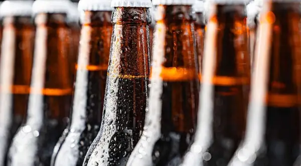 Bottiglie di birra ambrata, bagnate di condensa, perfette per chi cerca una birra piccola calorie.