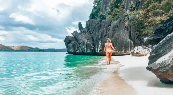 Frau genießt das türkisfarbene Wasser und den weißen Sandstrand auf den Philippinen. Ein perfekter Ort für Backpacking-Abenteuer.