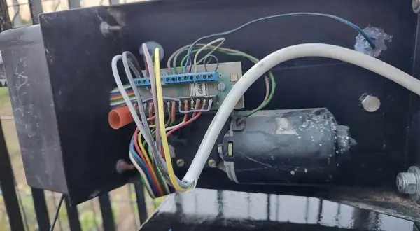 Mechanizm bramy: silnik, płytka drukowana i plątanina przewodów. Brama otwiera się ale nie zamyka, problem tkwi w tym skomplikowanym układzie.