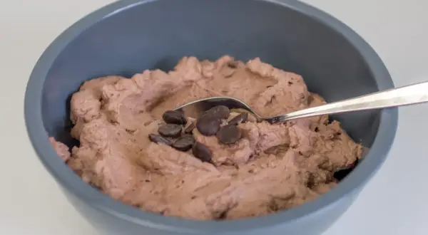 Schokoladige Sahnecreme mit Schokodrops in einer grauen Schüssel, bereit zum Genießen.