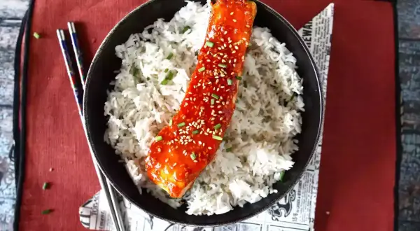 Łosoś w sosie gochujang z sezamem i ryżem, podany z pałeczkami.