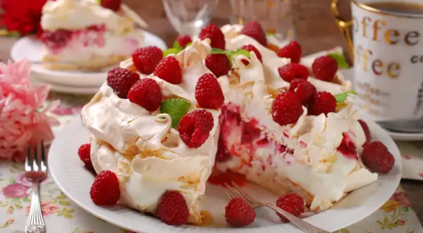 Beza z mascarpone i malinami, udekorowana świeżymi owocami i miętą.
