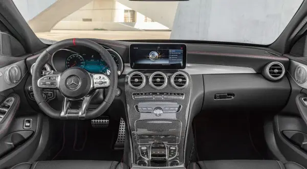 Interiör i en Mercedes W204 med sportratt, digital instrumentpanel och kolfiberdetaljer.