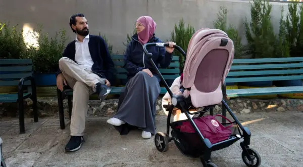 En man och en kvinna, som representerar muslimer i Sverige, sitter på en bänk med en barnvagn.