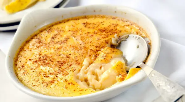 Un déliceux dessert crémeux, des oeufs au lait saupoudrés de cannelle, prêts à être dégustés avec une cuillère en argent.