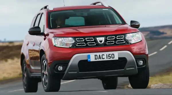 Röd Dacia Duster begagnad kör på en landsväg.