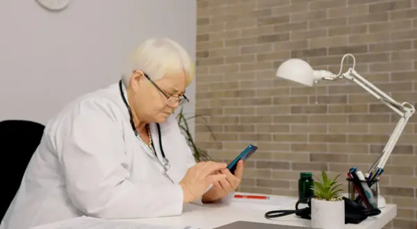Lekarka sprawdza na telefonie, jak długo jest ważne skierowanie do szpitala.