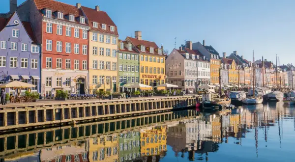 Kolorowe kamienice nad kanałem Nyhavn to obowiązkowy punkt na mapie kopenhaga co zobaczyć. Widać tu odbijające się w wodzie łodzie i budynki.