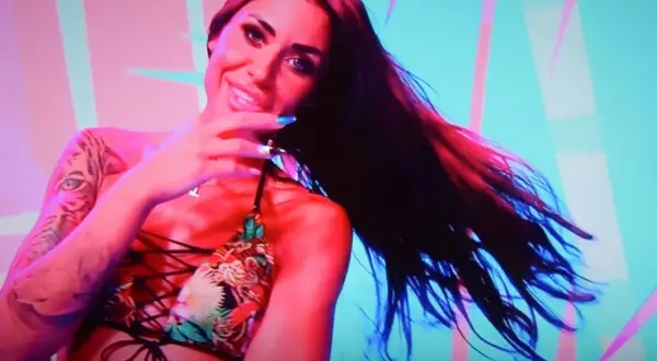 Stella z Love Island w kolorowym bikini, z tatuażem tygrysa na ramieniu, uśmiecha się do kamery.