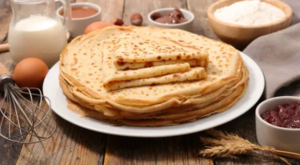 Una pila de crepes dorados, con ingredientes como leche, huevos y harina, evocan el origen de los crepes, un manjar sencillo y delicioso.