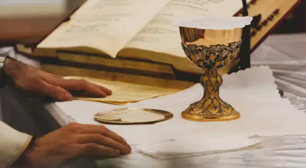 Złoty kielich i księgi liturgiczne na ołtarzu, przygotowanie do mszy. To moment, gdy wierni doświadczają cudu eucharystycznego.