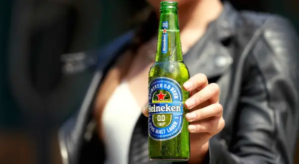 Mano che tiene una bottiglia di Heineken 0.0, la birra senza glutine, rinfrescante e gustosa.