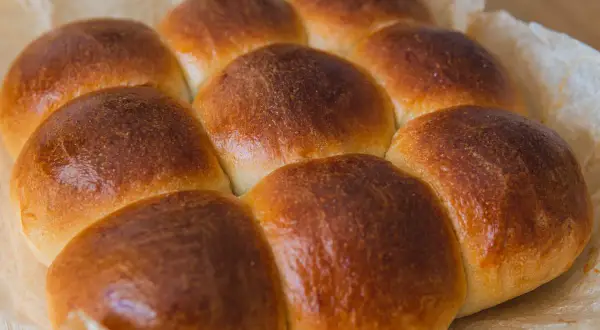 Złociste, pachnące szybkie bułeczki maślane, ułożone na papierze do pieczenia. Idealne na śniadanie.