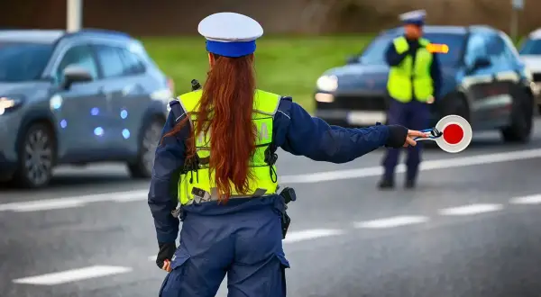 Policjantka kieruje ruchem, trzymając tarczę. Kierowcy powinni znać taryfikator mandatów, by uniknąć nieprzyjemności.