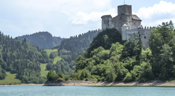 Zamek w Czorsztynie góruje nad jeziorem, otoczony zielonymi wzgórzami i lasami.
