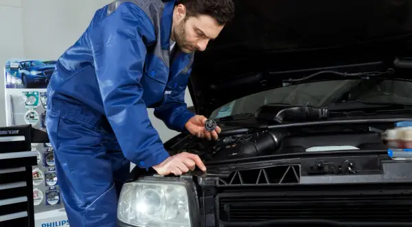 Mechanik wymienia żarówkę w Nissan Qashqai J10. Wymiana żarówki przód wymaga precyzji.