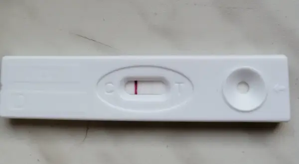 Blada kreska na teście ciążowym, widoczna przy literze "C", sugeruje wynik negatywny.
