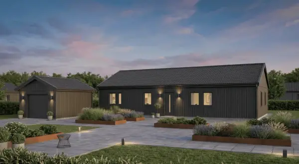 Modern dark gray house and detached garage with landscaped garden beds and paved driveway at dusk.