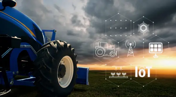 Trattore blu in un campo al tramonto, con icone che rappresentano l'agricoltura 4.0 esempi: IoT, pannelli solari, irrigazione e rete.