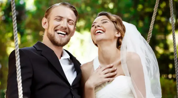 Coppia felice ride su un'altalena, perfetta per frasi per matrimonio e battesimo insieme.