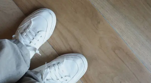 Piedi con scarpe bianche su un pavimento in laminato effetto legno. Questo pavimento spc cos'è? È un materiale resistente e moderno.
