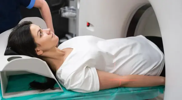 Frau liegt auf Liege für PET-CT-Untersuchung. Rote Laserlinien markieren Position.
