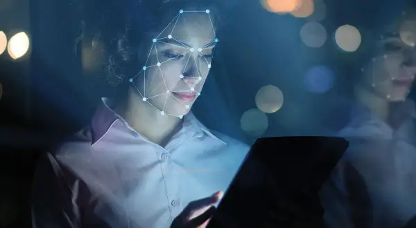 Donna con volto analizzato da rete neurale, tablet in mano. Il phygital significato è qui: fusione tra reale e virtuale.
