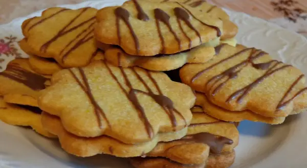 Stos ciastek z marmoladą, ozdobionych czekoladowymi paskami, wygląda apetycznie.