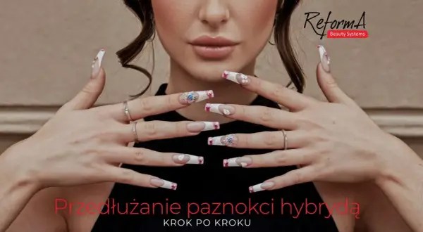 Dłonie z długimi, zdobionymi paznokciami hybrydowymi. Na jednym z paznokci widoczna jest tłusta płytka paznokcia, ozdobiona kryształkami.