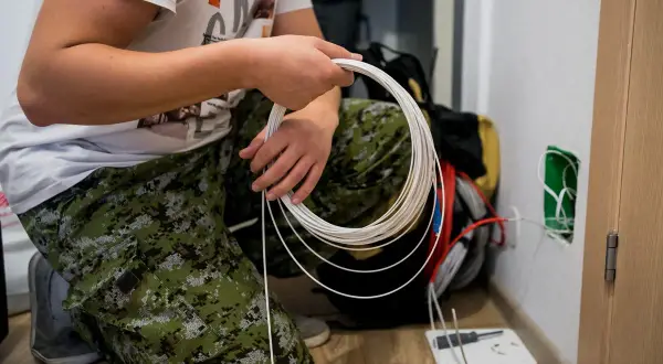 Un technicien prépare l'installation fibre gratuite, manipulant un câble blanc enroulé.
