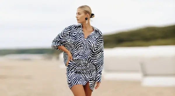Kobieta o figurze klepsydry plus size w sukience w panterkę na plaży.