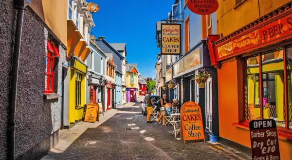 Färgglad gränd med butiker och caféer. En skylt för "Spögler's Continental Cakes Coffee Shop" syns tydligt, liksom en barberare. Kanske en trevlig plats att besöka efter en tur i Dublin.
