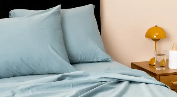 Soft, light blue sheets and pillows create a cozy bed. This material looks like the best material for sheets, promising comfort and style.
