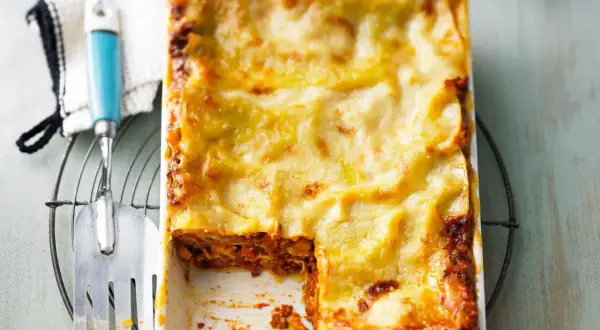 Ein frisch gebackenes, goldbraunes Lasagne-Rezept, original italienisch, mit einer Portion entnommen.