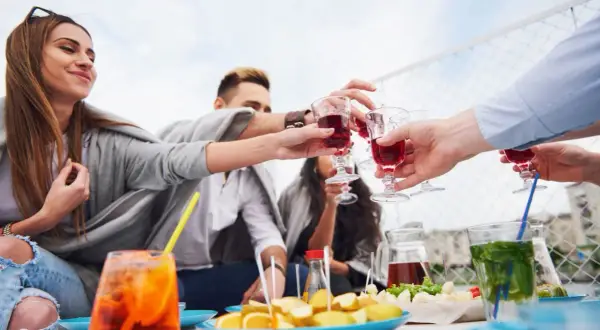 Grupa przyjaciół wznosi toast czerwonymi napojami. Czy to digestif? Pytanie, co to jest, pojawia się, gdy delektujemy się chwilą.