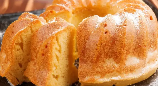 Puszysta babka wielkanocna, oprószona cukrem pudrem, kusi swoim złotym kolorem i delikatnym wnętrzem. Idealna na świąteczny stół.