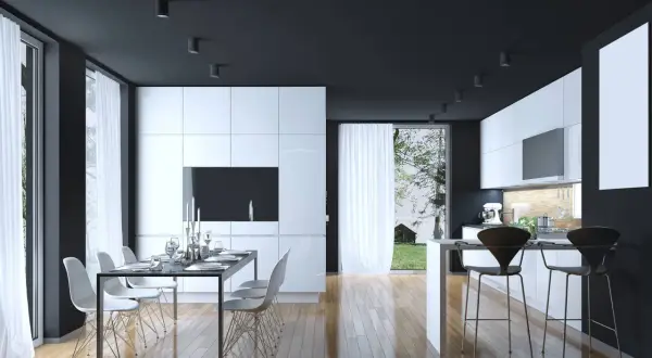 Cucina moderna con mobili bianchi lucidi, soffitto nero e pavimento in legno. Un tavolo da pranzo con sedie bianche e un'isola con sgabelli neri. Perfetti colori da abbinare al bianco e nero.