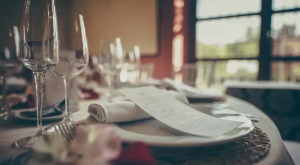 Mesa elegante con copas, cubiertos y menú. ¿Cuántas estrellas Michelin se pueden tener en una cena así?