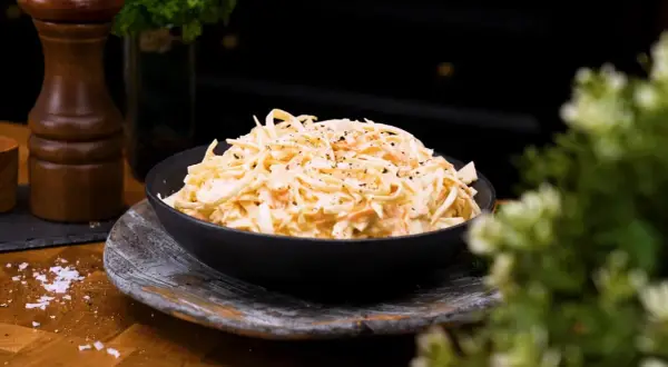 En skål med krämig, godaste coleslaw, toppad med nymalen svartpeppar. Perfekt tillbehör!