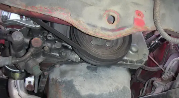 Detaljer från motorutrymmet, redo för kamkedja byte. Remmar och delar syns tydligt.