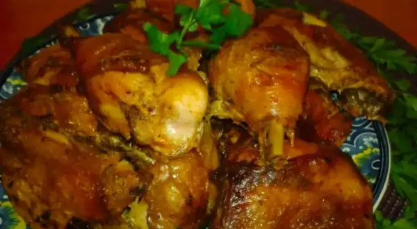 Pyszne, pieczone udka kurczaka w aromatycznej marynacie. Danie ozdobione świeżą natką pietruszki.
