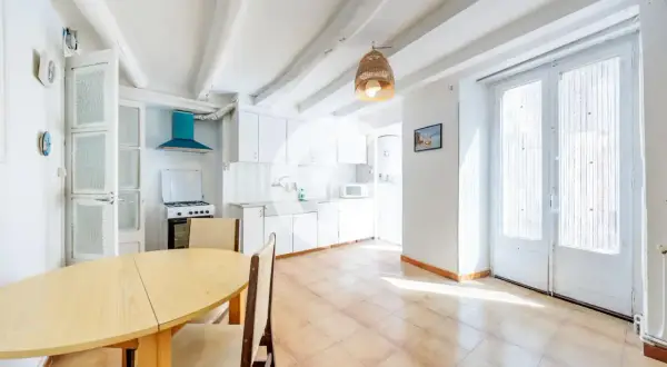 Cocina luminosa en una casa en Sallent, con vigas de madera en el techo, mesa de comedor y puertas acristaladas.