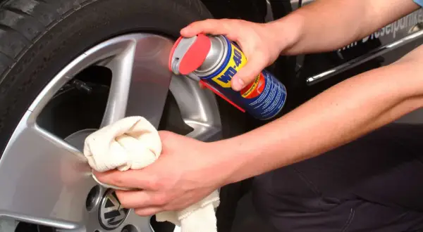 Hände reinigen Felgen mit einem Tuch und WD-40.