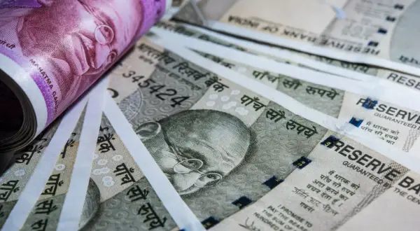 Stos banknotów, w tym fioletowy 2000 rupii i szare 500 rupii, z wizerunkiem Mahatmy Gandhiego. Waluta Indii.