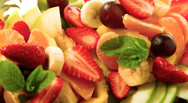 Bunter Obstsalat mit Erdbeeren, Bananen, Mandarinen, Äpfeln und Trauben. Ein erfrischendes, gekochtes Obst-Erlebnis.