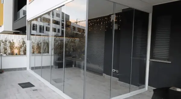 Veranda balcone con vetrate scorrevoli, luci decorative e piante. Spazio moderno e luminoso.