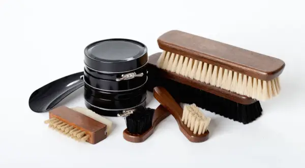 Ensemble d'outils cordonnier : cirages noirs, brosses en bois de différentes tailles et un chausse-pied.